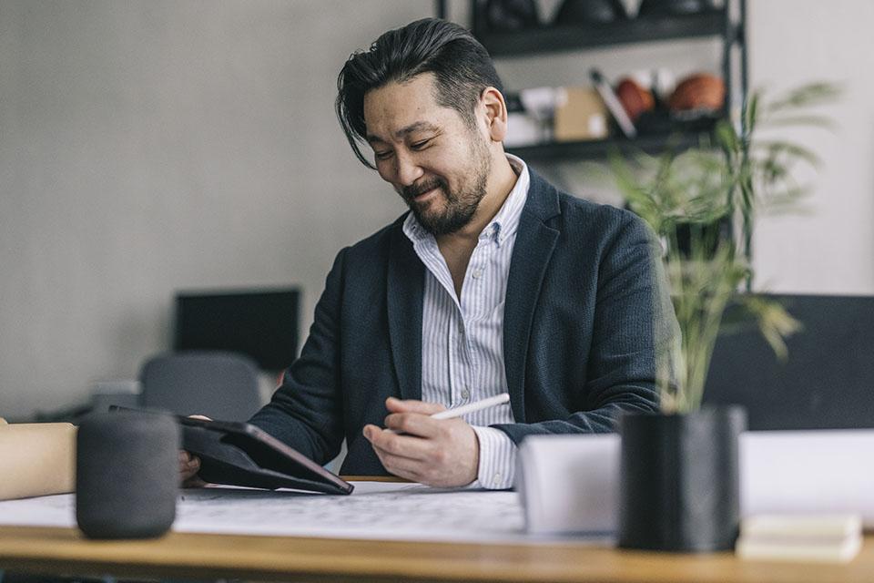 Business professional considering what his next career move will be while reviewing research on a tablet.